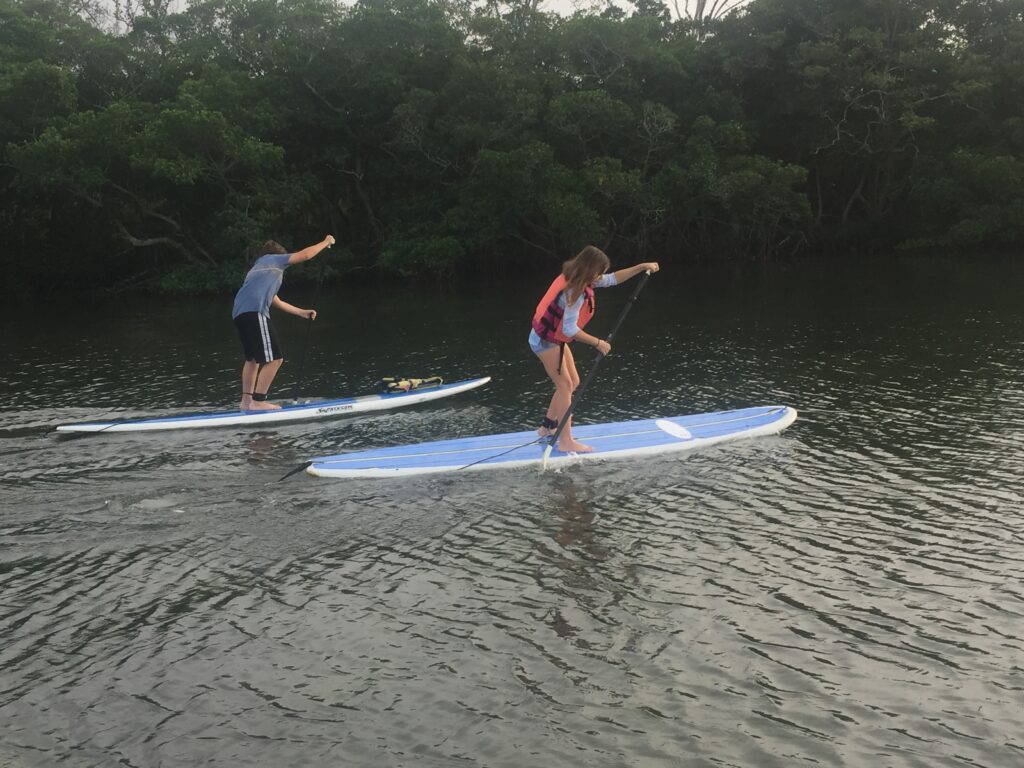 two kids racing on stand up paddleboards